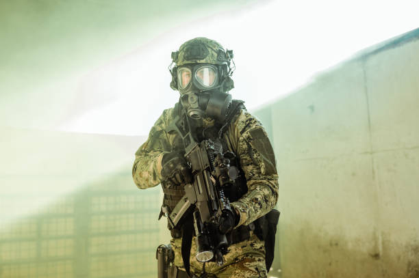 Military man holding a gun wearing a respirator